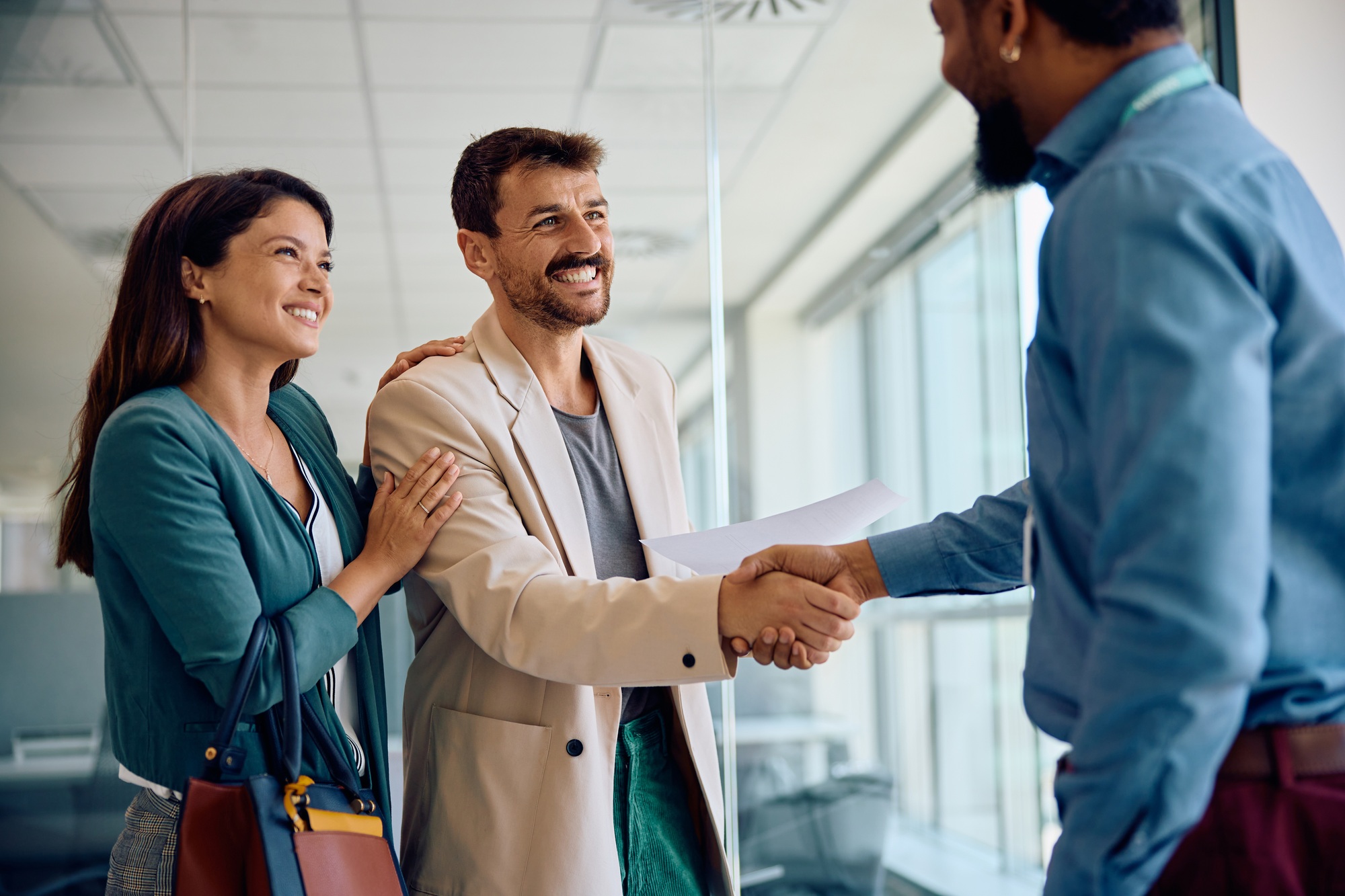 Happy couple handshaking with their financial advisor in the office.