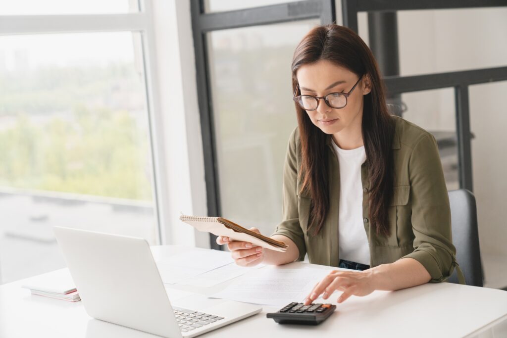 Young caucasian business woman counting funds, planning budget, paying bills online